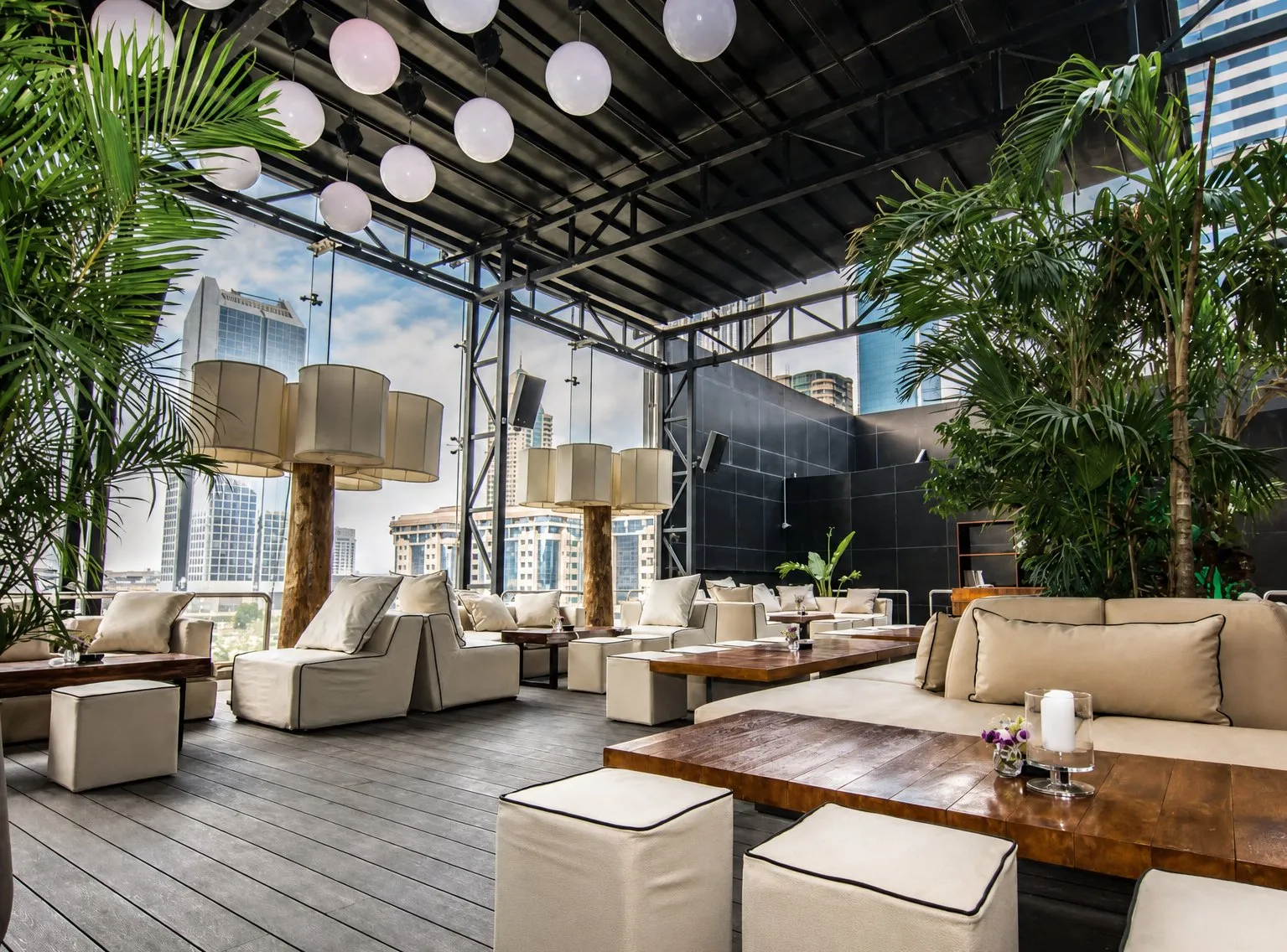 Rooftop lounge with trees, paper lanterns and low off-white seating