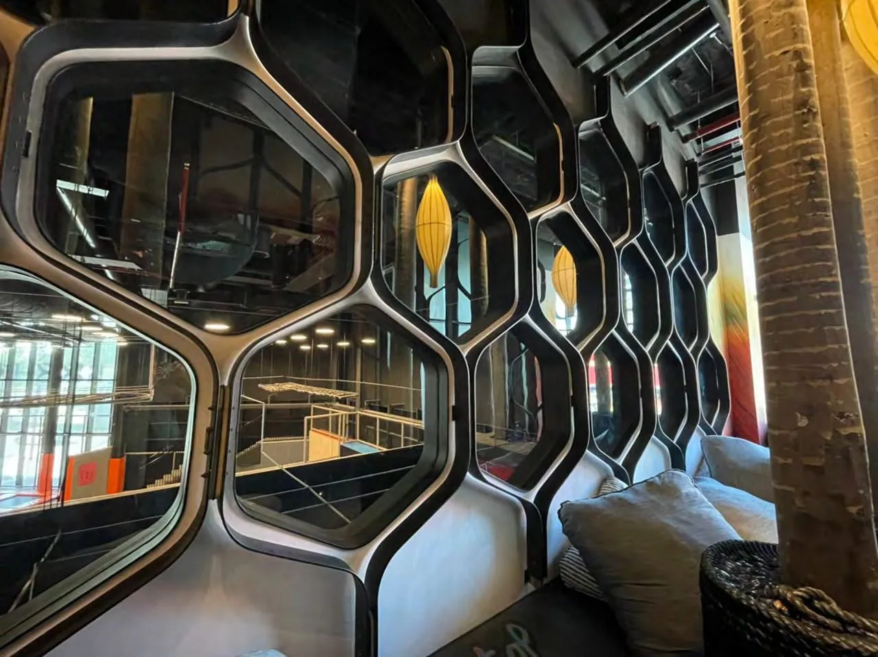 Dining room with hexagonal mirrored ceiling panels and tree-like timber columns
