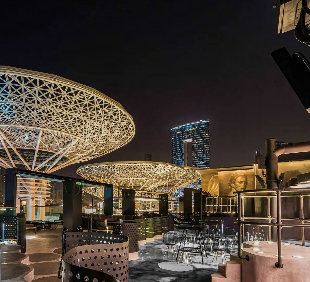 Rooftop terrace with gold lattice canopies and the Dubai skyline at night