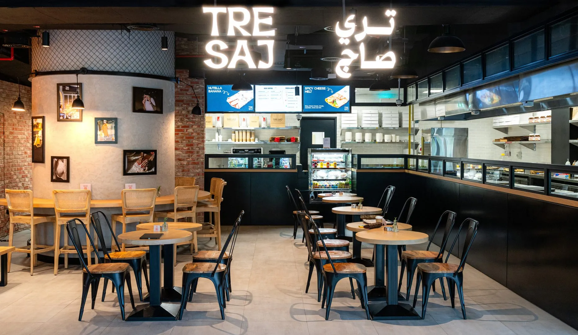 Tre Saj café interior with brick walls, black steel shelving and timber tables
