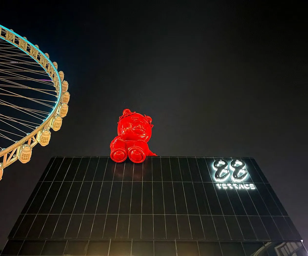 The rooftop at night with the red bear sculpture and Ain Dubai