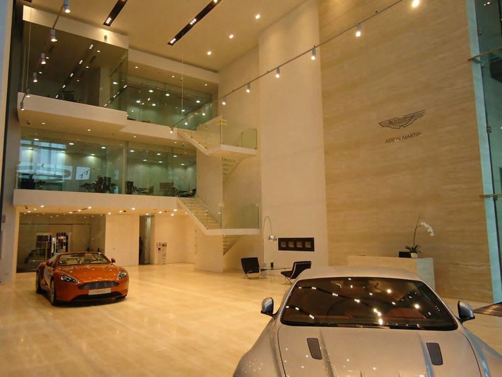 Double-height showroom hall in travertine with cars on display